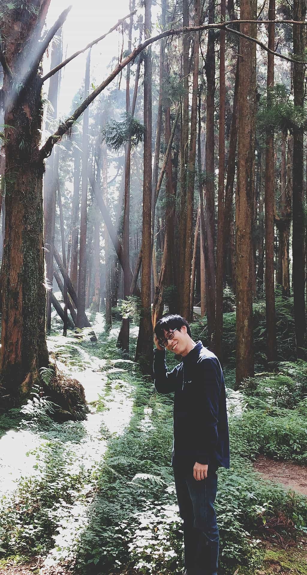 Tu standing in a sunlit forest